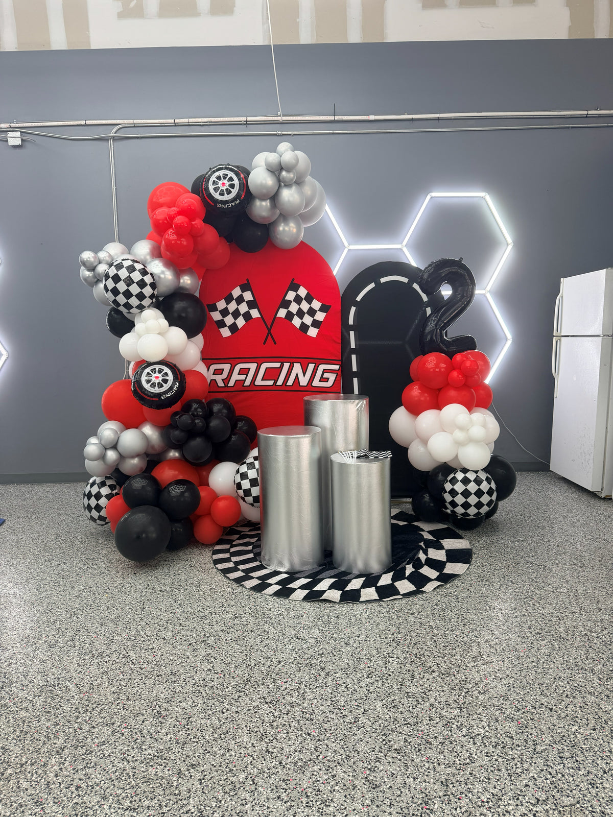 Red and black racing balloon decoration with large balloons; backdrops and pedestals priced separately.