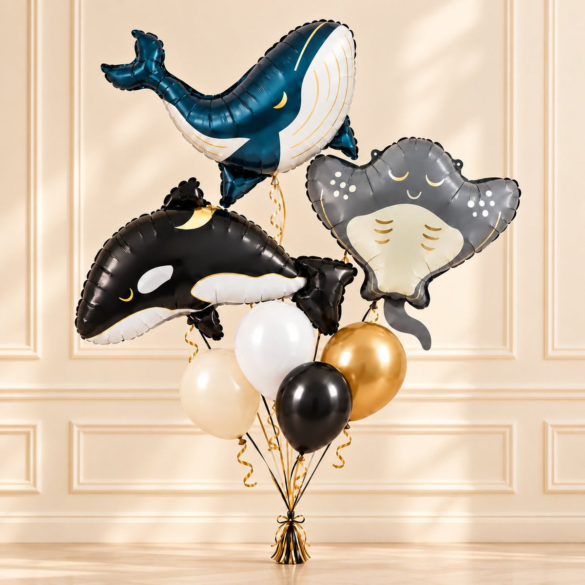 Whale, orca and stingray balloon bouquet with four coordinating latex balloons against a warm cream wall