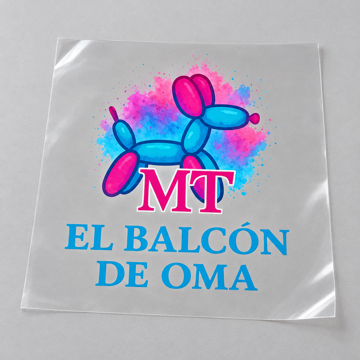 Example mockup of a clear DTF transfer sheet with El Balcón de Oma artwork; customers upload their own print-ready PNG