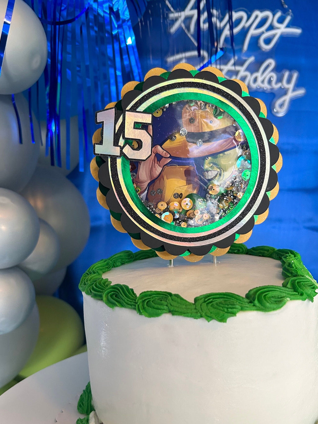 Green and yellow movie-themed topper with age fifteen displayed on a white cake with green frosting.