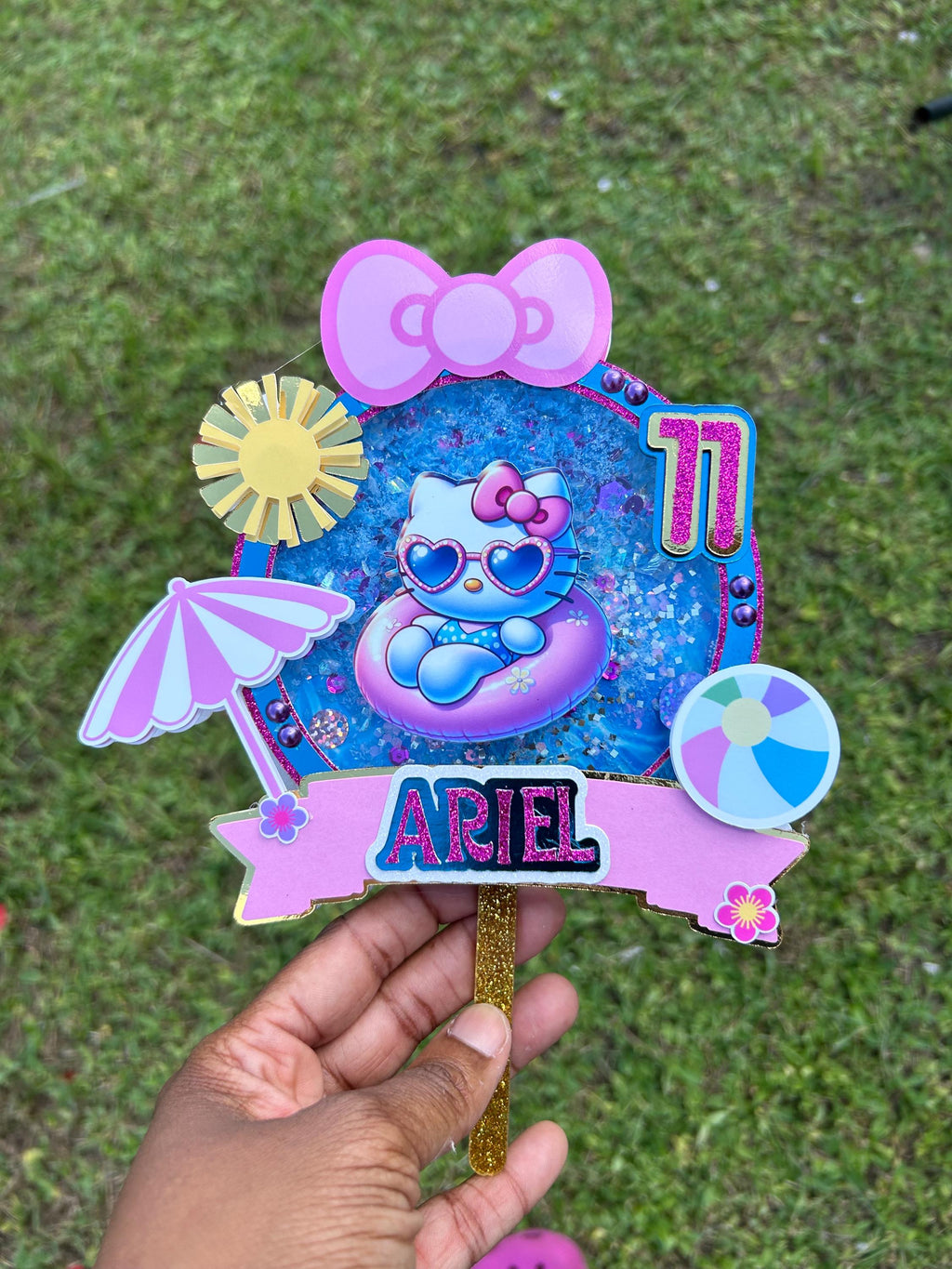Personalized Ariel pool party cake topper with age eleven, a cat in a pink pool float, beach ball, sun, parasol, and bow.