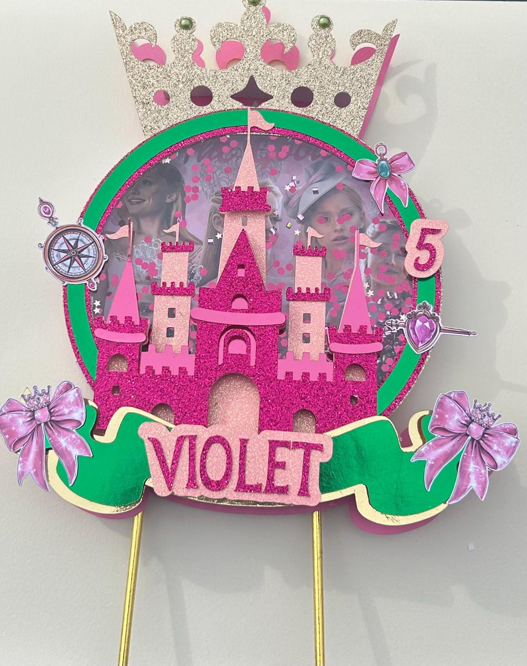 Personalized Violet pink castle cake topper with age five, gold crown, pink bows, green banner, and circular shaker background.