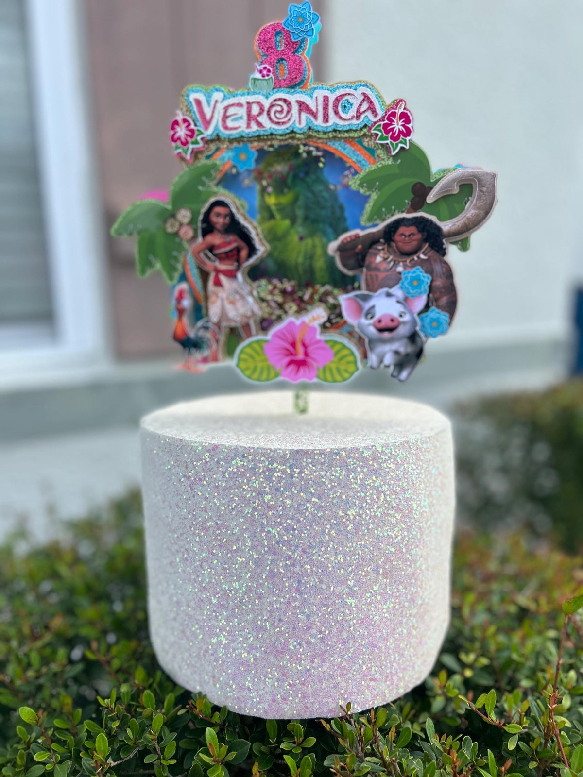 Veronica tropical birthday topper displayed on a glitter cake with age eight, palm trees, and island characters.