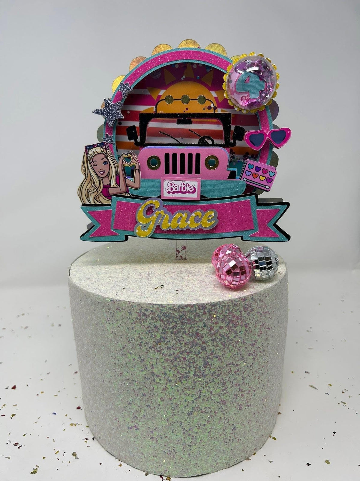 Fashion doll Jeep birthday topper personalized with Grace and age four on a glitter display cake with small disco balls.
