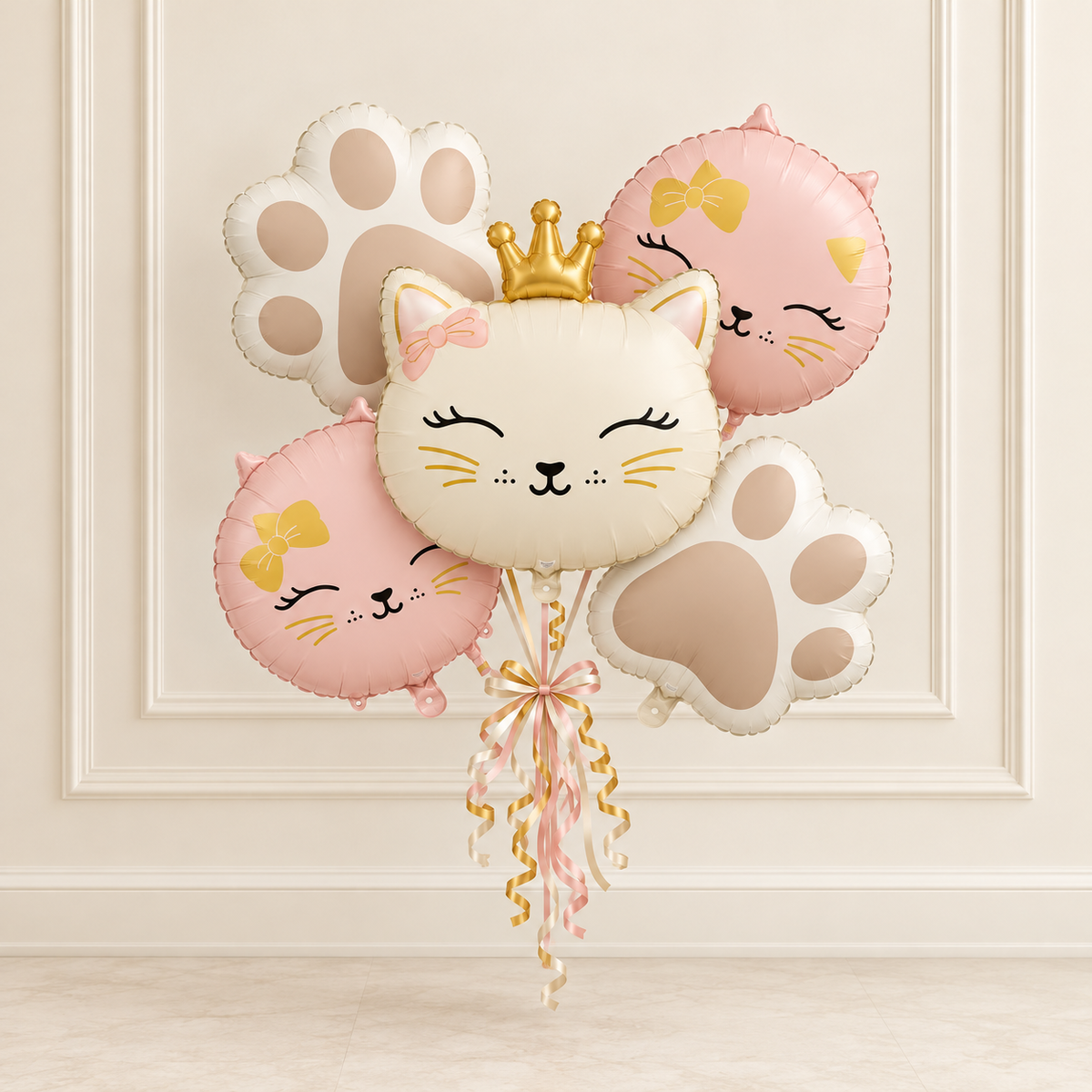 Five matte princess kitty balloons in pink and cream with paw balloons against a cream wall with decorative molding